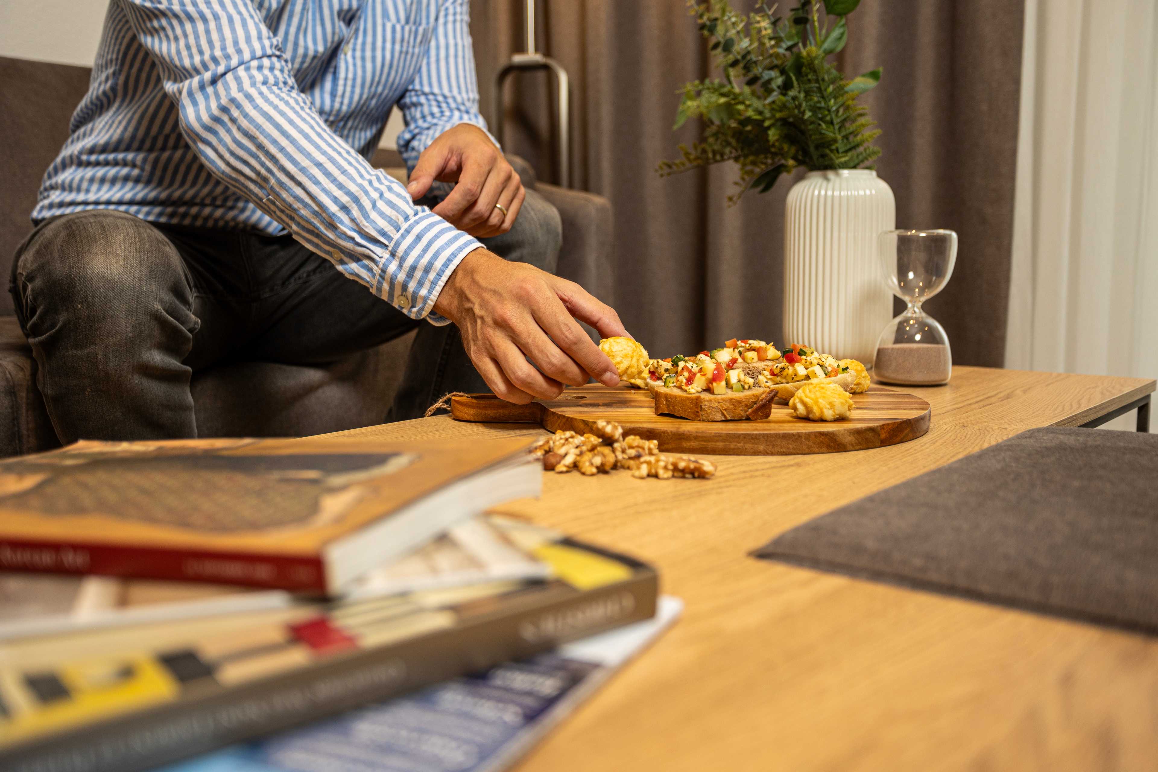 A man enjoying a snack in his cozy apartment at La Maison Suisse Döttingen