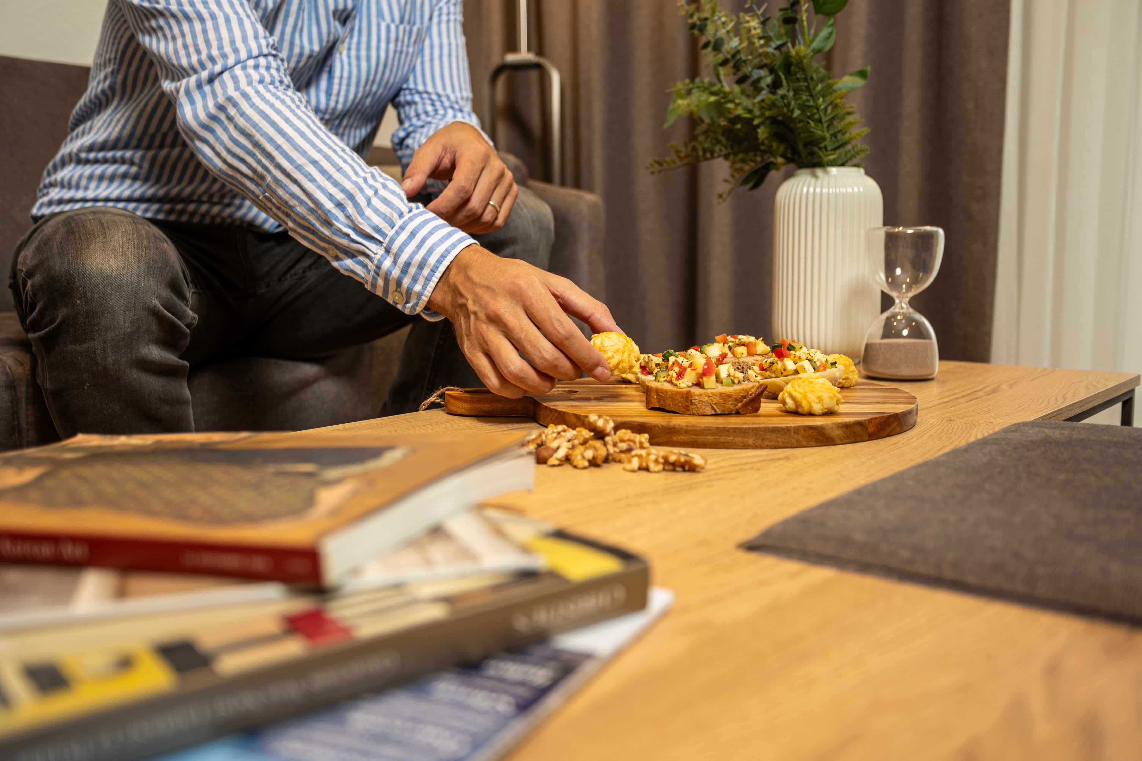 Ein Mann geniesst einen Snack in seinem gemütlichen Apartment bei La Maison Suisse Döttingen